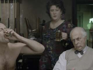 Shannah Laumeister and Bruce Willis sit stripped to the waist behind a poker steel